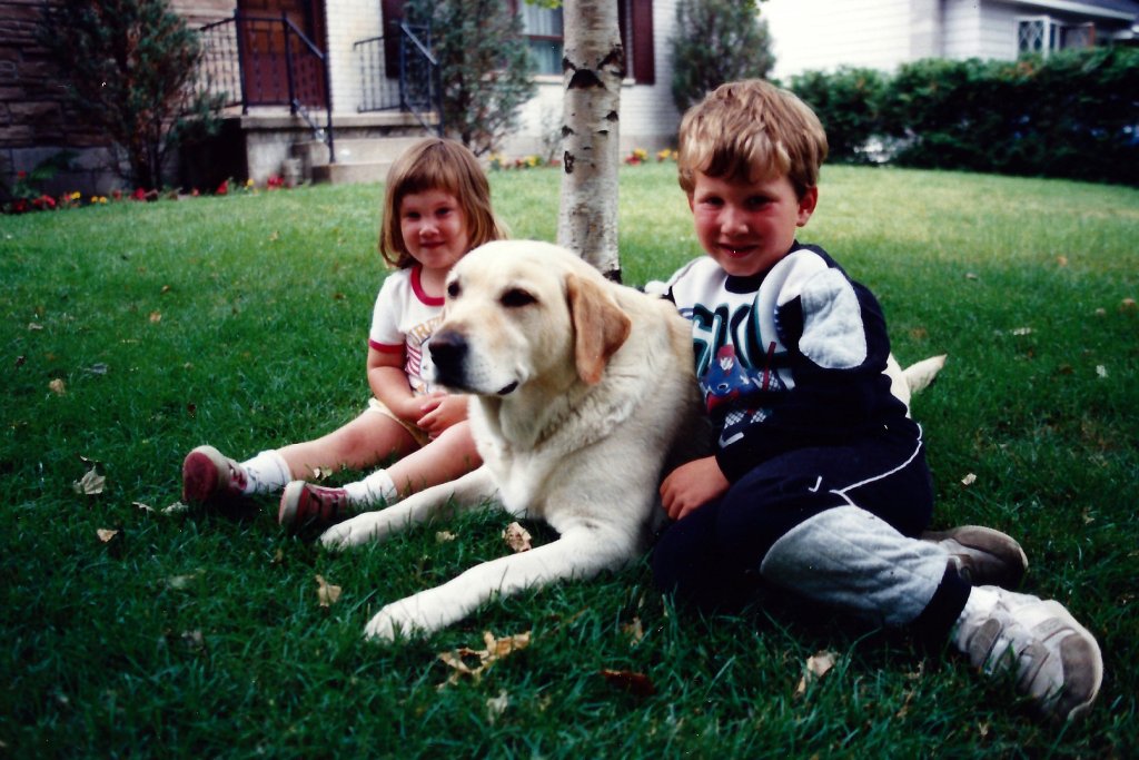 Kids with dog sitting in the front yar